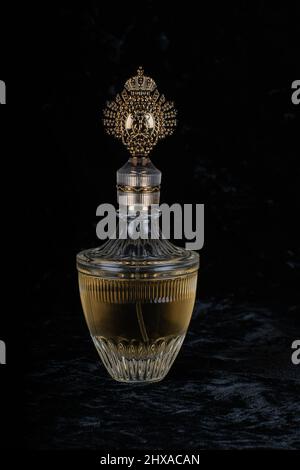 Bouteille de parfum dorée en verre de style roi sur fond de velours noir. Banque D'Images