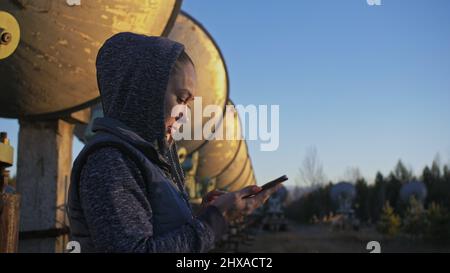 Une femme étudiante-opérateur de l'institut de physique terrestre solaire surveille les équipements de communication dans le téléphone mobile. Radiotélescope solaire à faisceau unique. Banque D'Images