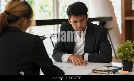 A insisté sur le fait que le directeur général masculin d'Asie lisait les informations sur les documents administratifs et travaillait avec sa directrice marketing féminine au bureau. Banque D'Images