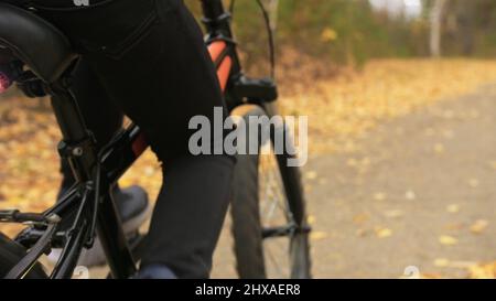 L'un des enfants de race blanche rides moto road in autumn park. Little girl riding noir orange cycle en forêt. Enfant va faire location sports. Motion Biker ride Banque D'Images