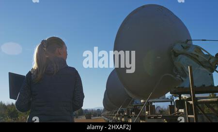 Une femme étudiante-opérateur de l'institut de physique terrestre solaire surveille les équipements de communication dans un ordinateur portable. Radiotélescope solaire à faisceau unique. DIM Banque D'Images