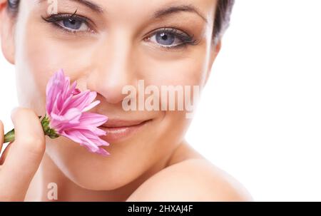 Frais comme une fleur. Une jolie jeune femme souriant à l'appareil photo tout en renifant une fleur rose. Banque D'Images