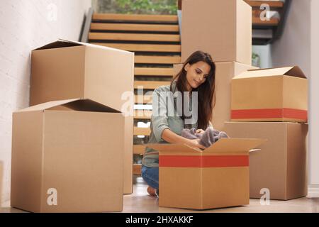 Passons à des pâturages plus verts. Une jeune femme emballant des boîtes dans un appartement. Banque D'Images