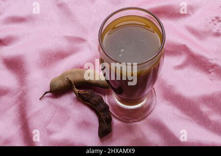 Verre à boire avec jus de Tamarind sur fond rose Banque D'Images