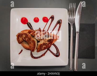 Pintxos artisanaux ou tapas de foie gras sur un toast avec glaçure balsamique et confiture d'oignons sur une assiette dans un restaurant à Pampelune, Espagne Banque D'Images