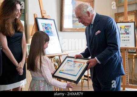 Le Prince de Galles rencontre Isabella Grover, âgée de 7 ans, gagnante nationale du concours de création de timbres « héros de la pandémie » de Royal Mail, tout en regardant les créations gagnantes à Clarence House à Londres. Date de la photo: Jeudi 10 mars 2022. Banque D'Images