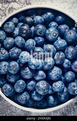 Versez une dose de bleuets frais et savoureux dans un bol. Fruits de la forêt pleins de vitamines et d'antioxydants. Banque D'Images