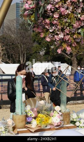 Tokyo, Japon. 11th mars 2022. Une femme dépose un bouquet de fleurs et prie pour les victimes du tremblement de terre et du tsunami de 3,11 à Tokyo le vendredi 11 mars 2022. Le Japon a marqué le 11th anniversaire du grand tremblement de terre de l'est du Japon qui a tué quelque 20 000 personnes en 2011. Credit: Yoshio Tsunoda/AFLO/Alay Live News Banque D'Images
