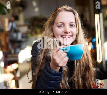 Le café me permet de me rafraîchir et de me ravitailler. Portrait d'une jeune femme attrayante appréciant un cappuccino dans un café. Banque D'Images