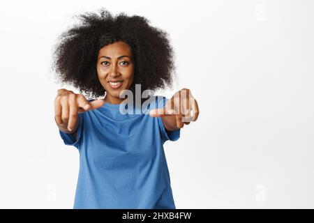 Félicitations. Souriante afro-américaine moderne femme pointant du doigt vers un appareil photo, vous choisissant, félicitant ou choisissant, invitant des gens, debout Banque D'Images