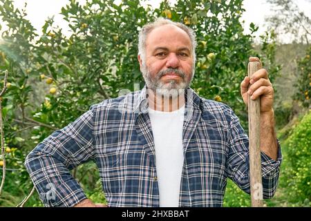 Portrait d'un jardinier mûr barbu travaillant dans le verger. Prendre soin du jardin. Jardinage de printemps. Élagage saisonnier des arbres. Banque D'Images