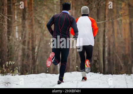 deux coureurs mâles qui cournent le sentier d'hiver dans la forêt Banque D'Images