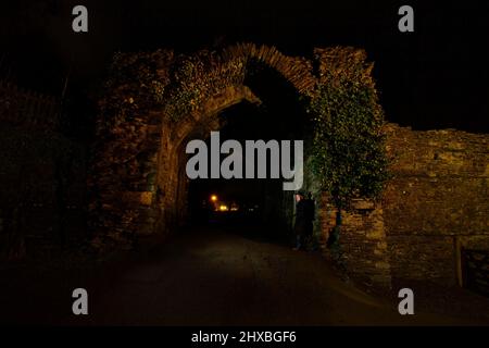 Un homme debout sous une arche la nuit dans la ville cornish de Launceston Banque D'Images