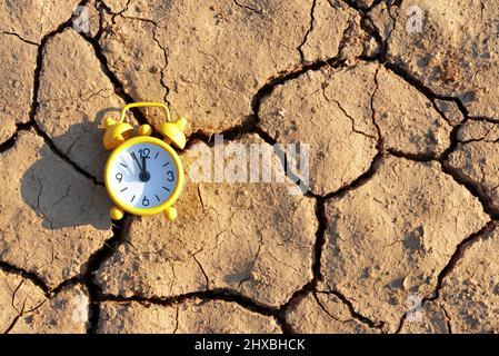 Réveil avec cinq minutes avant douze heures sur terre aride fissurée. Concept de changement climatique ou de réchauffement de la planète. Banque D'Images