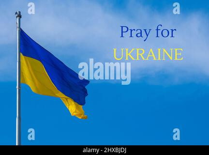 PRIEZ POUR LE TEXTE DE L'UKRAINE sur le drapeau national ukrainien flotte dans le vent contre le ciel bleu. Symbole national du peuple ukrainien - bleu et jaune. IND Banque D'Images