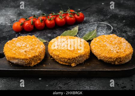 Patties de hamburger au saumon cru, sur fond de table noir en pierre foncée Banque D'Images