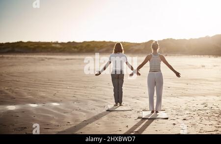 Suivez votre chemin paisible avec le yoga. Photo d'un couple méconnaissable pratiquant le yoga sur la plage. Banque D'Images
