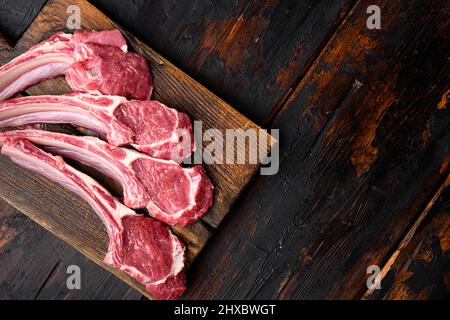 Côtelettes de viande d'agneau steaks, sur fond de table en bois foncé, plan de dessus, avec espace pour le texte Banque D'Images