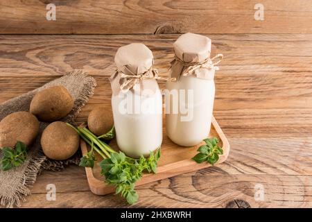 lait de pomme de terre végétalien en deux bouteilles sur un plateau en bois et une table rustique. substitut de boisson. alimentation saine Banque D'Images