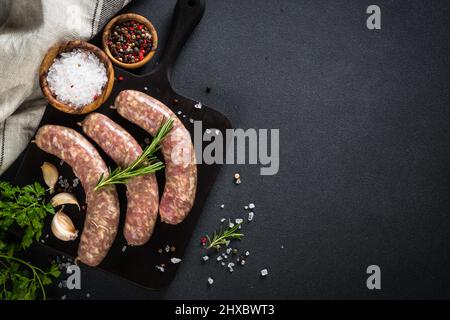 Bratwurst ou saucisses sur planche à découper avec épices à table noire. Banque D'Images