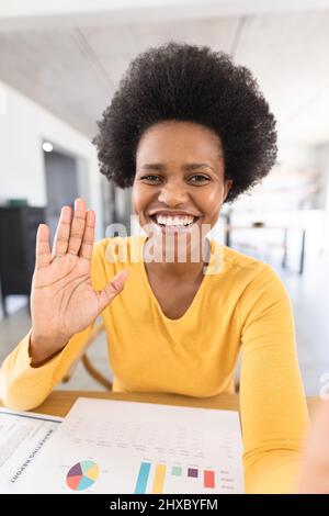 Portrait d'une femme freelance afro-américaine de taille moyenne agitant sur appel vidéo au bureau à domicile Banque D'Images