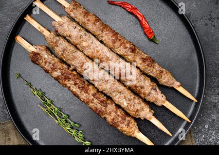 Mutton kebab brochettes chiches, sur plaque, sur fond noir de table en pierre sombre, vue de dessus plat Banque D'Images