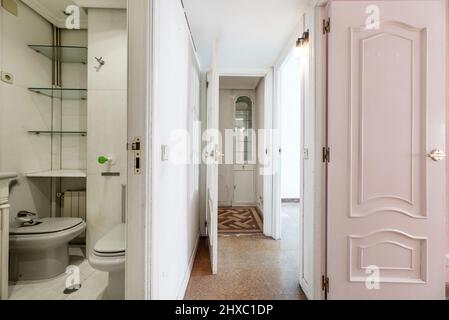 Couloir d'une maison résidentielle avec plancher en liège, porte d'accès à une toilette et vitrine en bois et en verre en arrière-plan Banque D'Images