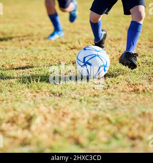 Chargement de l'objectif. Prise de vue de deux enfants non identifiables jouant au football à l'extérieur par une journée ensoleillée. Banque D'Images