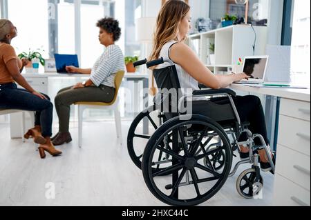 Elle ne manque jamais un jour au bureau. Photo d'une femme d'affaires assise dans son fauteuil roulant tout en travaillant à son bureau. Banque D'Images