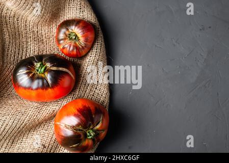 Tomates rouges-noires de la variété de coeur de boeuf sur fond noir. Banque D'Images