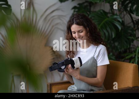 Femme curieuse avec des lunettes VR futuristes innovantes dans les environs de plantes exotiques tropicales Banque D'Images