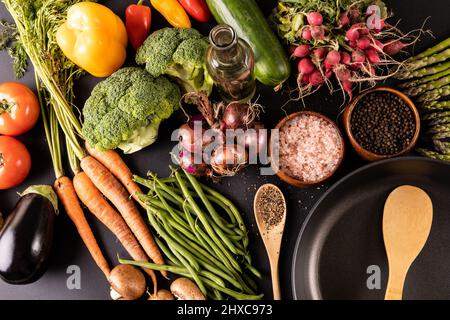 Vue en grand angle de divers légumes avec épices, herbes, huile et poêle sur la table Banque D'Images