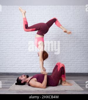 Jeune couple s'amusant à la maison avec quelques acro yoga main à main avec la jambe jouer pose. Banque D'Images