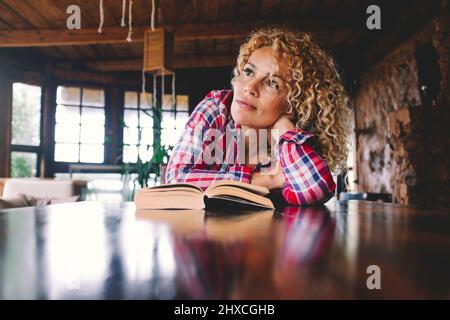 Femme, Jeune, boucles, Blonde, Table, Prop up, perdu dans la pensée, Livre, portrait Banque D'Images