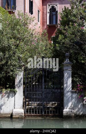 Jardin caché derrière une porte en treillis à Venise, en Italie Banque D'Images