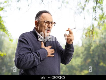 Homme mature fumant et toussant à l'extérieur Banque D'Images