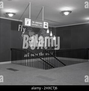 1957, historique, panneau « to Coaches » au-dessus de l'escalier au niveau supérieur du nouveau terminal aérien de West London, Kensington, Londres, Angleterre, Royaume-Uni, Avec un motif « Fly BOAC » sur le mur. Le terminal aérien de Cromwell Road était un service d'enregistrement pour les passagers voyageant sur British European Airways (BEA) et BOAC au départ de l'aéroport d'Heathrow. Ils ont ensuite été transportés par autocar jusqu'à l'aéroport. Banque D'Images