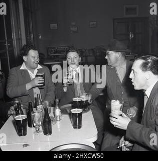 1950s, historique, Cheers boyos, quatre steelworks gallois ayant une bonne boisson après une dure journée de travail, assis autour d'une table au club social du complexe d'acier Abbey Works, Port Talbot, pays de Galles, Royaume-Uni Banque D'Images