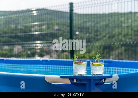 Deux cocktails sur une piscine portable dans un jardin avec vue imprenable sur les montagnes. Banque D'Images