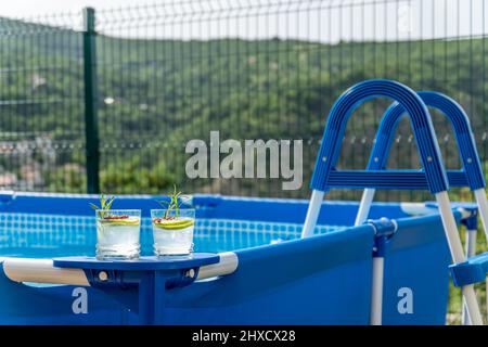 Deux cocktails sur une piscine portable dans un jardin avec vue imprenable sur les montagnes. Banque D'Images