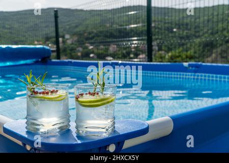 Deux cocktails sur une piscine portable dans un jardin avec vue imprenable sur les montagnes. Banque D'Images