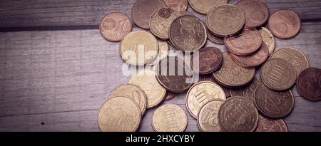 Une collection de pièces en euros en condition partiellement très utilisée sur une surface en bois Banque D'Images