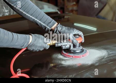 Mains d'un peintre qui grince une voiture pour peindre dans un atelier mécanique. Banque D'Images