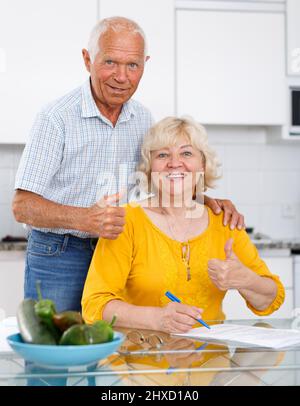 Couple d'âge mûr à la table de cuisine remplissant les documents Banque D'Images