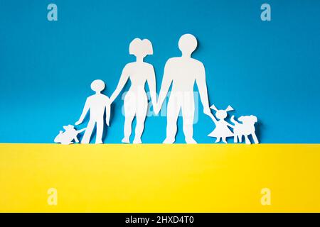 couloir humain pour sortir les civils du conflit en ukraine. découpe de papier d'une famille sur le drapeau de l'ukraine. réfugiés de guerre. concept de famille. Banque D'Images