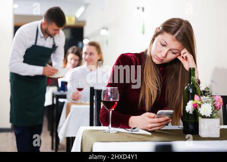 Femme élégante en colère s'attend à ce que l'homme pour le dîner dans le restaurant de luxe Banque D'Images