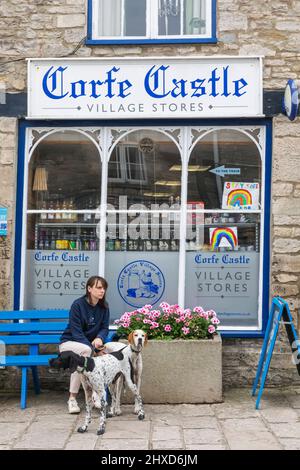 Angleterre, Dorset, île de Purbeck, Corfe Castle Village, femme et chiens devant les magasins de Corfe Castle Village Banque D'Images