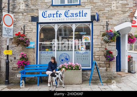 Angleterre, Dorset, île de Purbeck, Corfe Castle Village, femme et chiens devant les magasins de Corfe Castle Village Banque D'Images