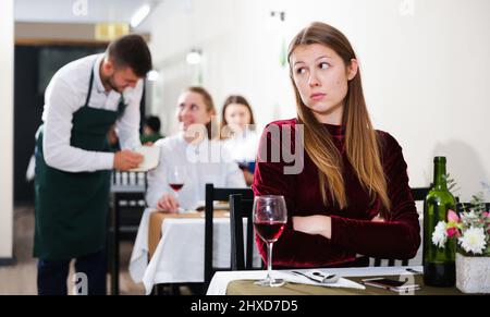 Femme élégante en colère s'attend à ce que l'homme pour le dîner dans le restaurant de luxe Banque D'Images