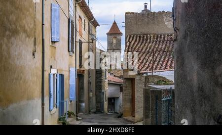 Rue du village à Azillanet avec vue sur le clocher de l'église Saint Laurent. Le territoire municipal appartient au Parc naturel régional du Haut Languedoc. Banque D'Images